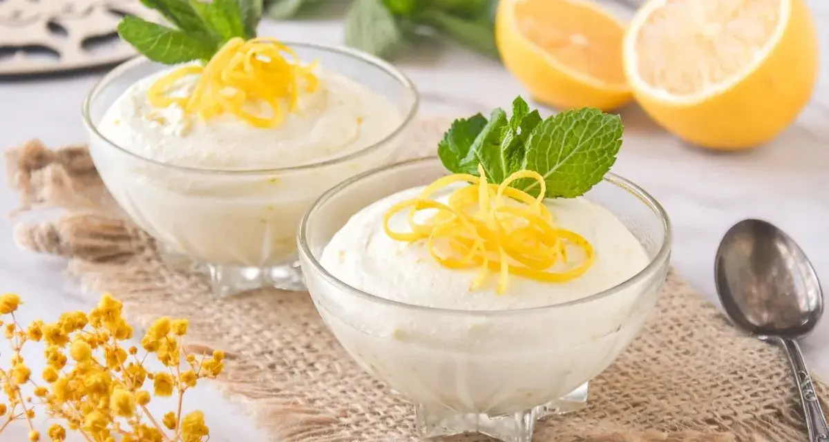 Dos copas de cremoso mousse de limón con leche condensada, decoradas con ralladura de limón y menta.