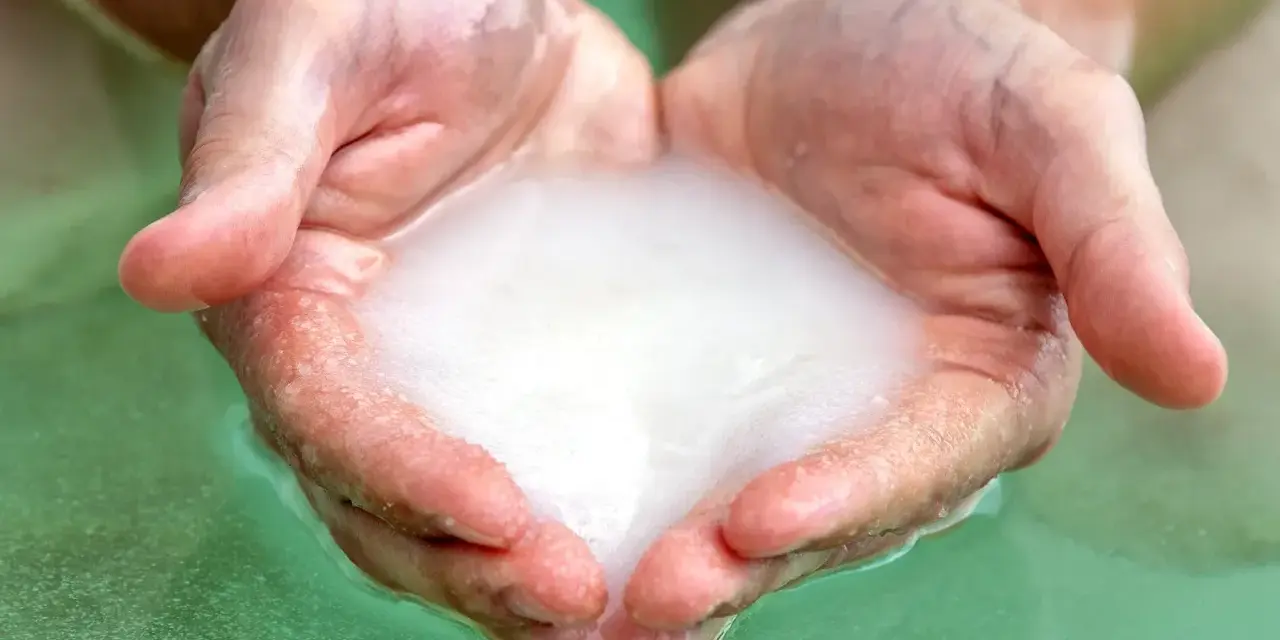 Hands cupped, holding foamy water, ready for a relaxing magnesium foot soak.