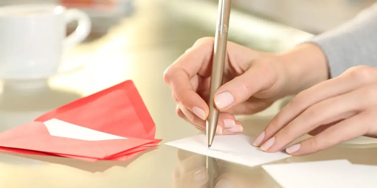 Main tenant rédige un modèle d'autorisation parentale TAM. Une tasse de café et une enveloppe rouge sont à proximité.