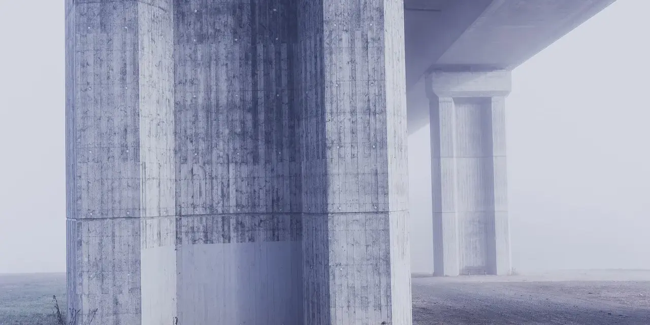 Betonowe filary mostu w gęstej mgle. Różne klasy ekspozycji betonu tworzą ciekawe tekstury.