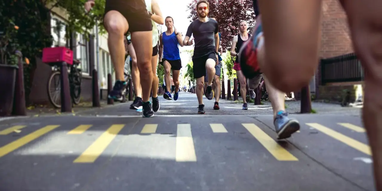En grupp löpare kämpar sig fram på asfalten, redo att springa halvmaraton. Gula linjer på vägen markerar banan.