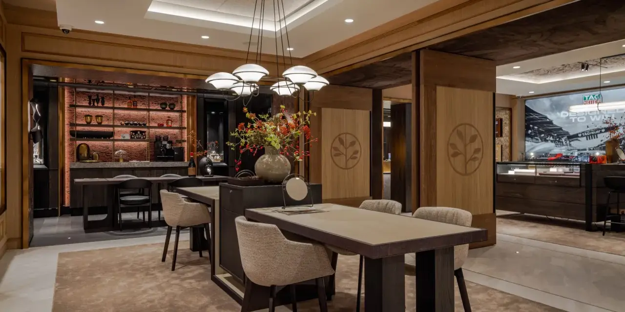 Interno di un elegante **progetto gioielleria** con tavoli in legno, sedie imbottite, un'area bar e vetrine espositive.
