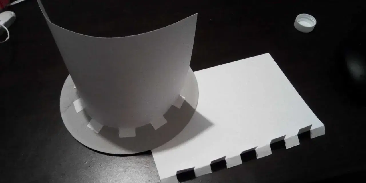 Chapeau en carton en cours de création, avec des pièces découpées et un patron.