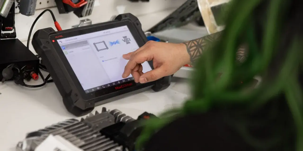 Mechanic uses a diagnostic tablet to connect to a car's ecm.