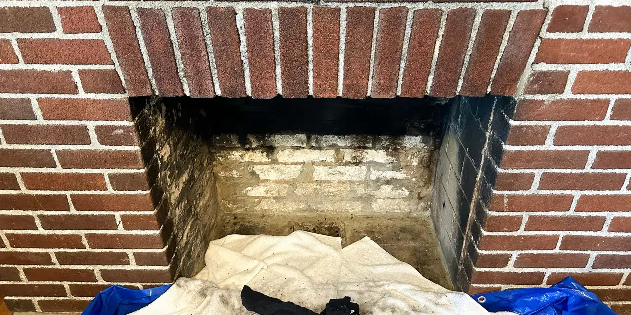 Camino in mattoni pronto per la pulizia. Il braciere è vuoto, ma c'è un allarme per la stufa a pellet.