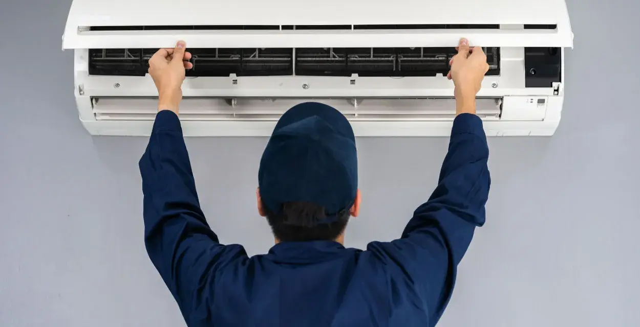 Tecnico controlla un condizionatore che non raffredda, aprendo il pannello frontale per ispezionare i filtri.