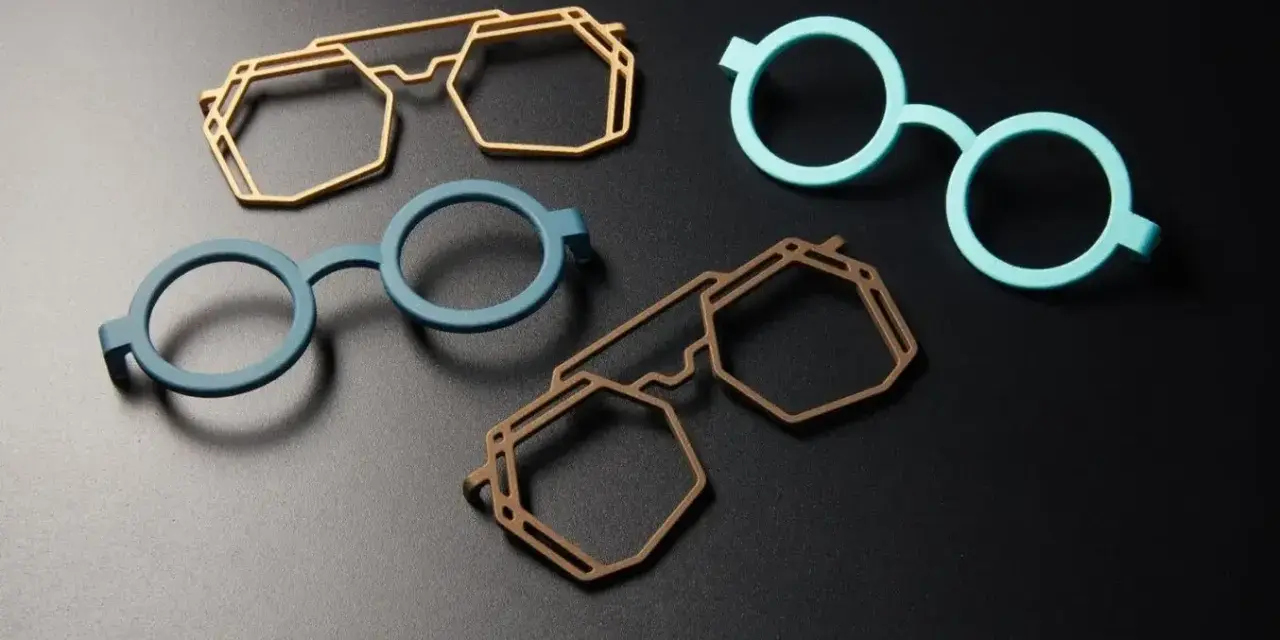 Four colorful, modern 3d printing glasses frames in geometric and round shapes, displayed on a dark surface.
