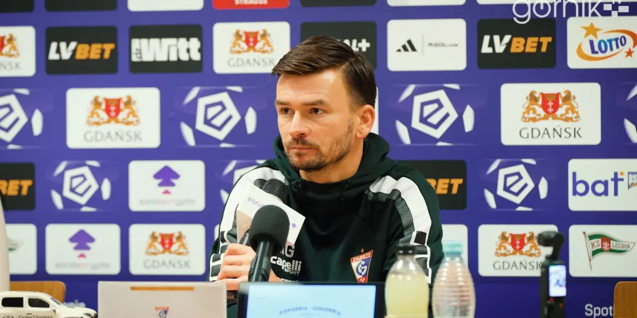 Trener rozmawia o lechia transfery. Na ścianie logo Lechii Gdańsk.