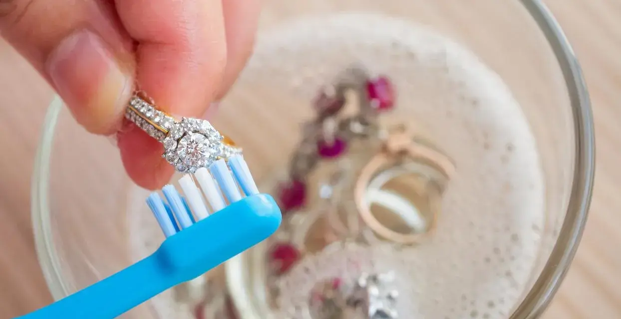 Limpia tu plata con bicarbonato y vinagre. Un anillo de diamantes se cepilla suavemente en un bol con joyas burbujeantes.
