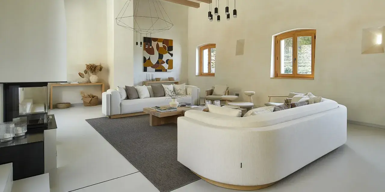 Salón moderno con sofás blancos, chimenea y suelo de microcemento sobre azulejos.
