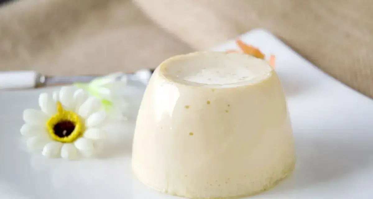 Delizioso budino fatto in casa, servito su un piatto bianco con un fiore decorativo.