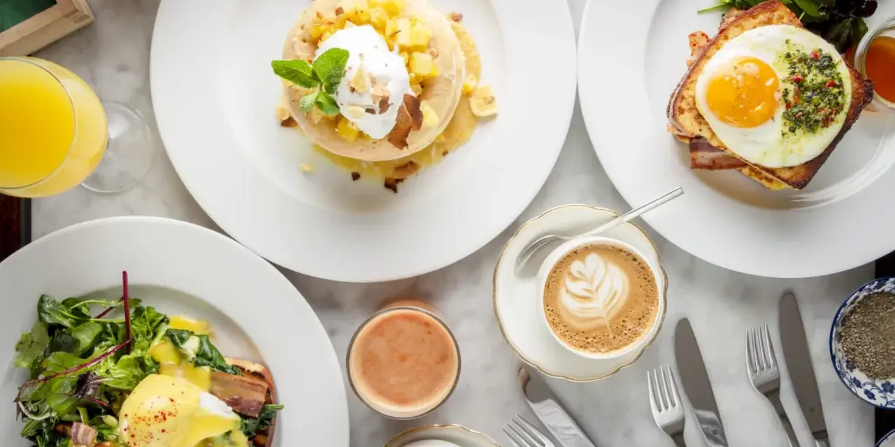 Ein köstlicher Brunch in Berlin: Pancakes mit Früchten, Eggs Benedict und Croque Madame mit Spiegelei. Dazu Kaffee und Saft.