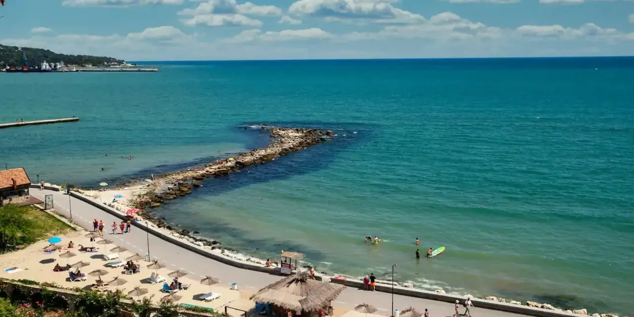 Piękna pogoda w maju w Bułgarii. Słoneczny dzień nad turkusowym morzem, plaża z leżakami i parasolami, ludzie kąpią się i spacerują.