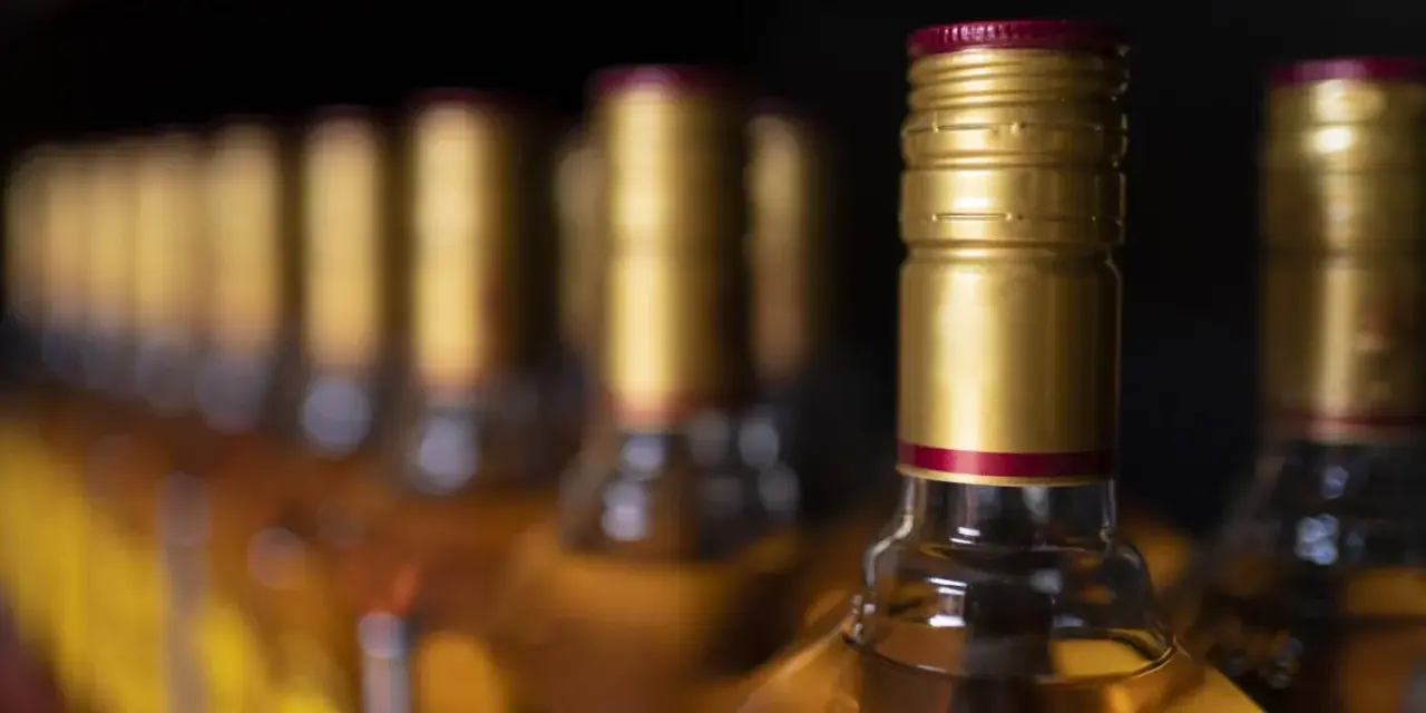 Rząd butelek z alkoholem, idealnych na podróż. Zastanawiasz się, ile alkoholu do samolotu można zabrać?
