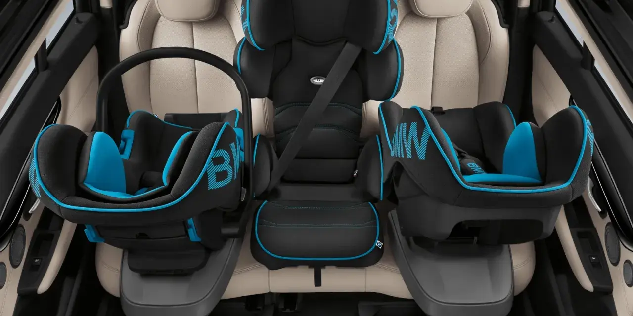 Trois sièges auto pour enfant, noir et bleu, installés sur des sièges en cuir clair. Le transport enfant en voiture est sécurisé.