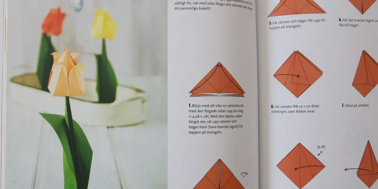 Vackra vika pappersblommor i form av tulpaner, en klassiker inom origamikonsten. En orange tulpan i förgrunden, med en röd och en gul i bakgrunden.