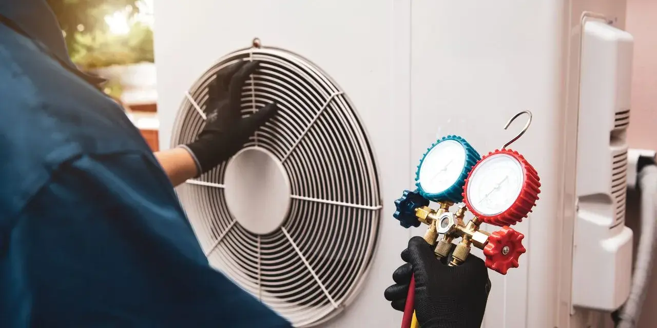 Technicien effectuant l'entretien d'une pompe à chaleur air/air, vérifiant la pression avec un manomètre.