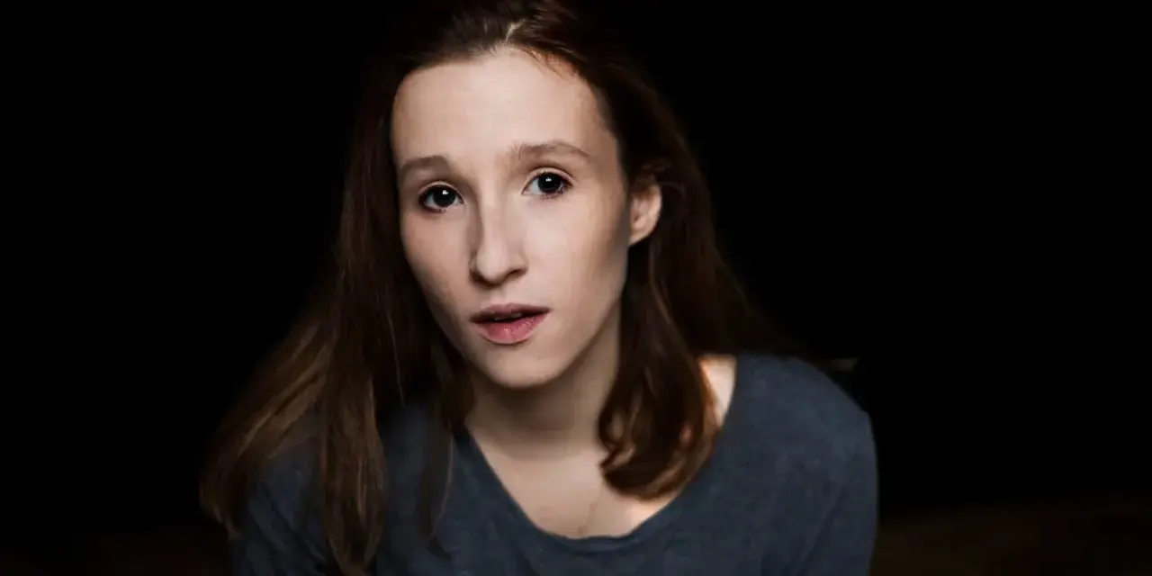 Portret Anny Paligi z ciemnymi włosami i w szarej bluzce, patrzącej wprost przed siebie.