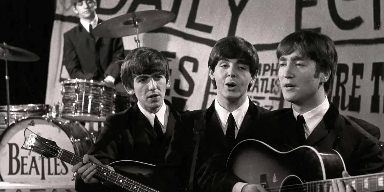 Les Beatles, le groupe le plus connu au monde, jouent sur scène. John Lennon et Paul McCartney chantent, George Harrison joue de la basse, Ringo Starr est à la batterie.