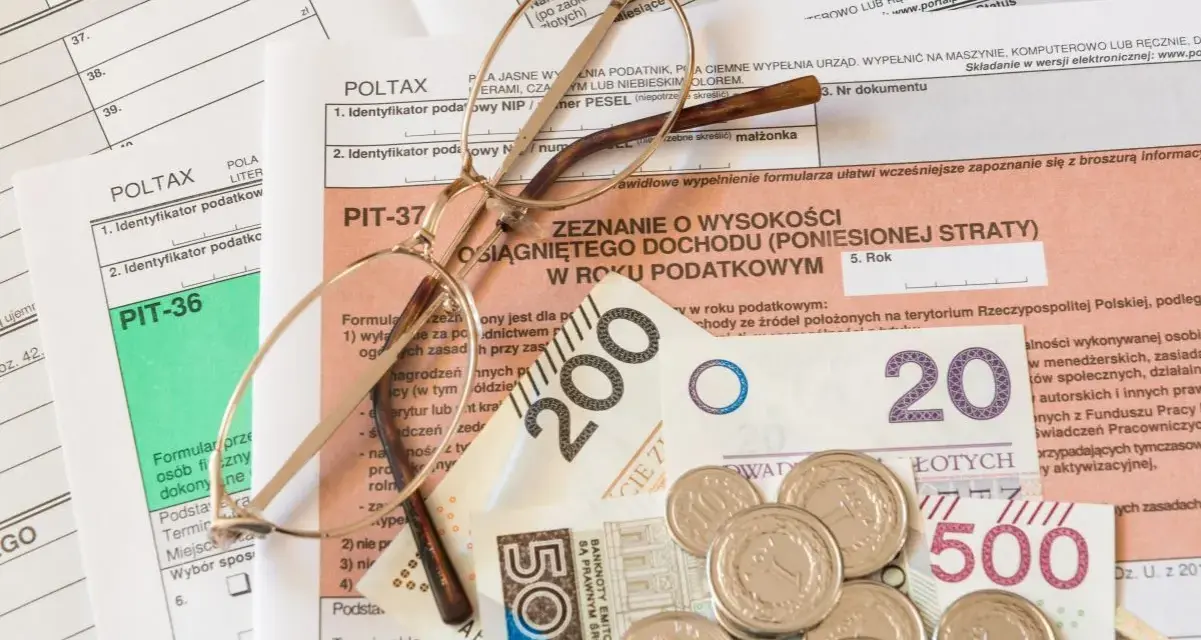 Okulary na dokumentach podatkowych PIT i pieniądzach. Zrozumienie, z czego wynika niedopłata podatku, wymaga analizy tych dokumentów.