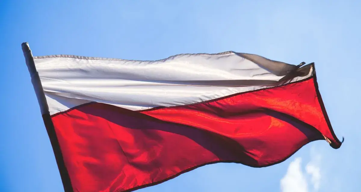 Flaga Polski, biało-czerwona, powiewa na tle błękitnego nieba.