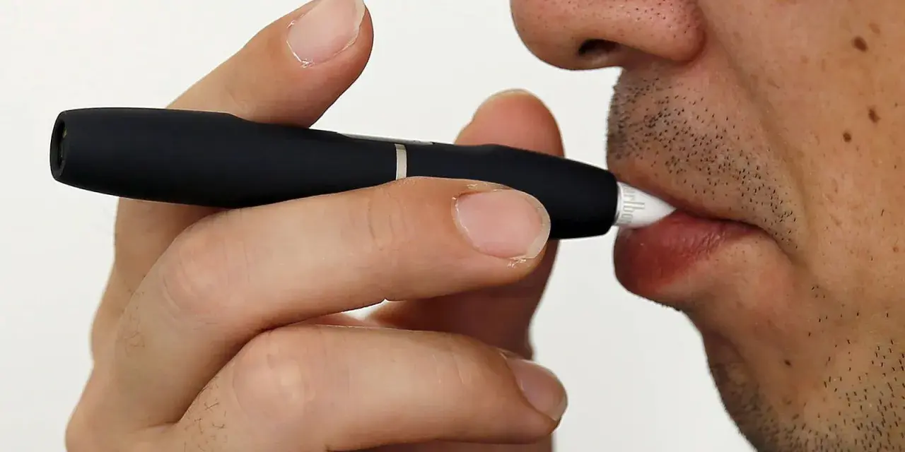 Persona usa un dispositivo IQOS. Las opiniones médicas sobre IQOS son variadas, pero este dispositivo calienta tabaco en lugar de quemarlo.