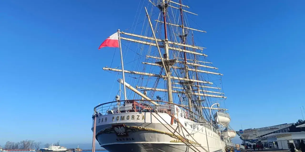 Duma polskiego żeglarstwa, żaglowiec "Dar Pomorza", cumuje przy nabrzeżu. Biało-czerwona flaga dumnie powiewa na maszcie.