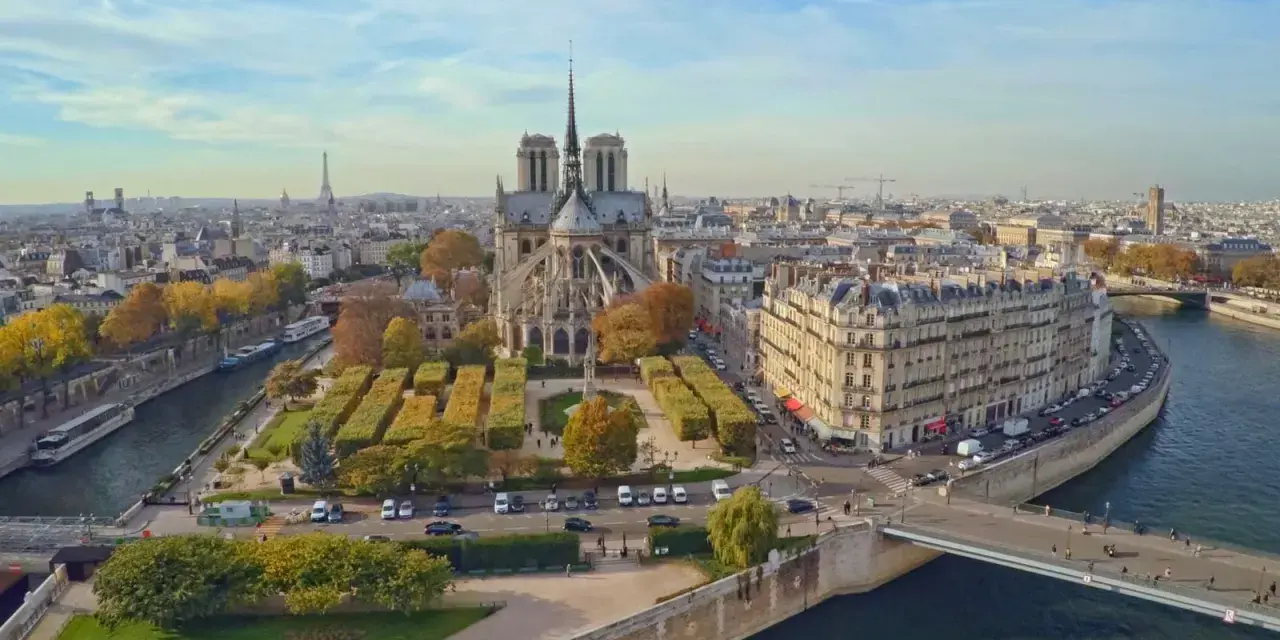 Vista aérea de la Île de la Cité en París, con la majestuosa Catedral de Notre Dame en el centro, rodeada de edificios históricos y el río Sena.