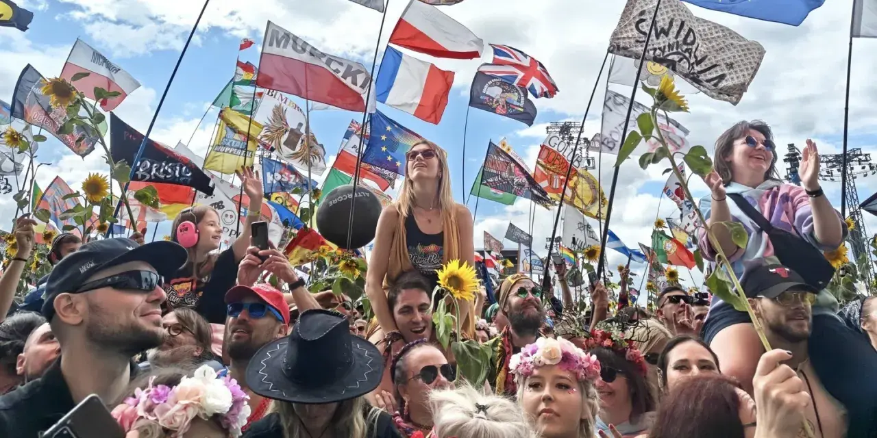 Tłum na festiwalu Poland Rock 2026, z flagami i słonecznikami. Ludzie cieszą się muzyką i atmosferą.