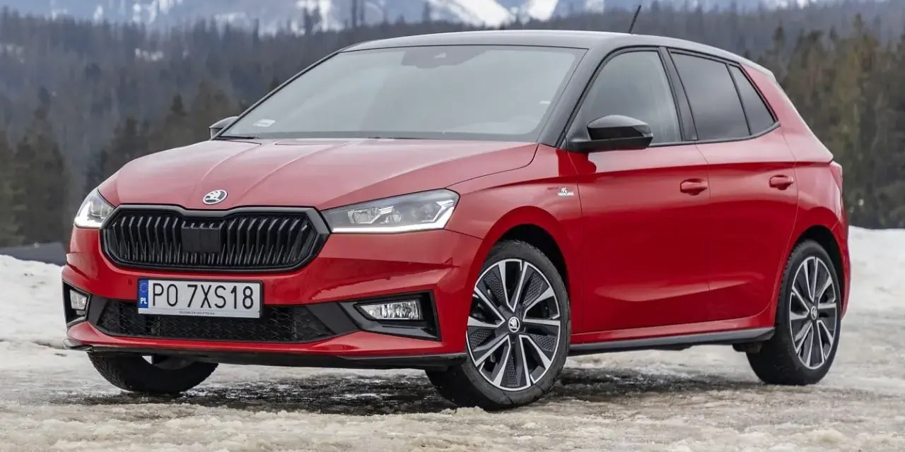 Czerwona Skoda Fabia Monte Carlo z czarnym dachem na tle ośnieżonych gór.