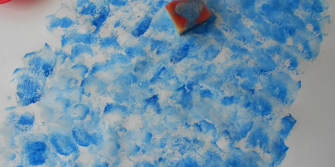 Peinture à l'éponge sur toile, créant un effet de vagues bleues et blanches. Une éponge est posée sur la toile.