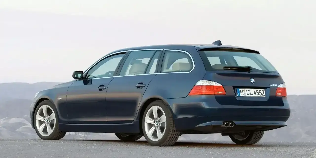 Granatowe BMW E61, kombi, stoi na pustej drodze.