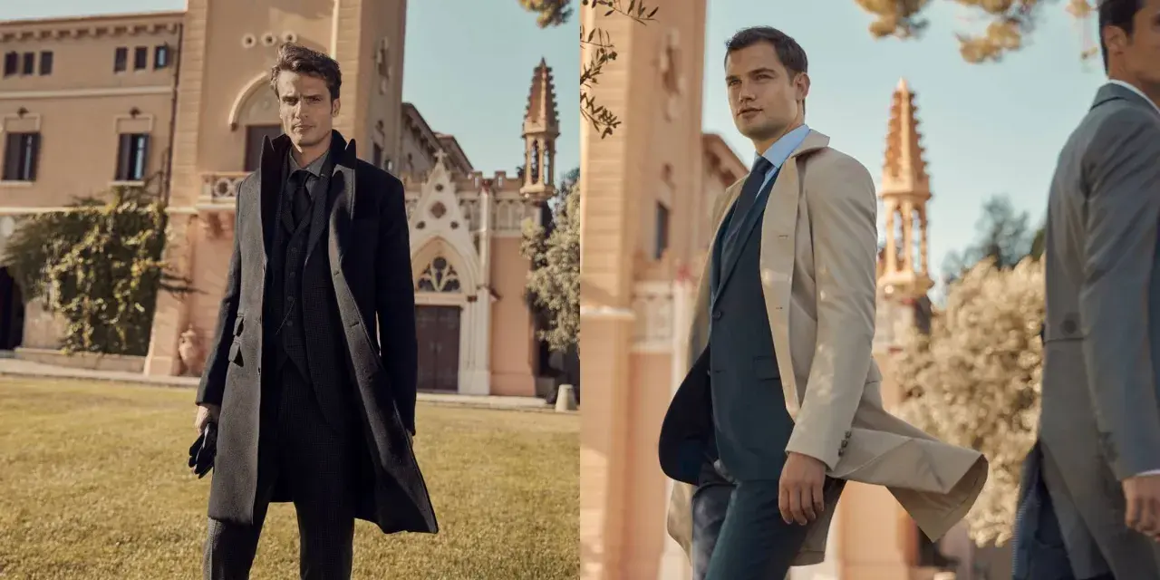Uomo elegante con un outfit con trench, in posa davanti a un edificio storico.