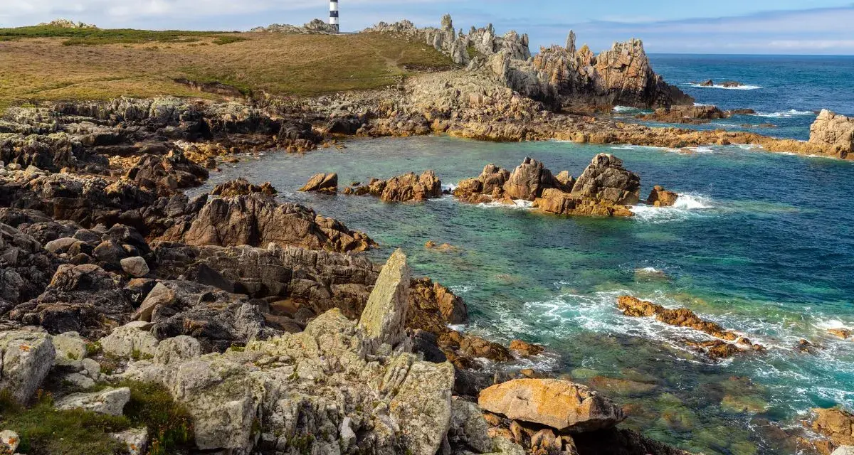 Phare noir et blanc sur une côte rocheuse et sauvage d'Ouessant. Combien de temps pour visiter Ouessant ? Une journée suffit pour admirer ce paysage.