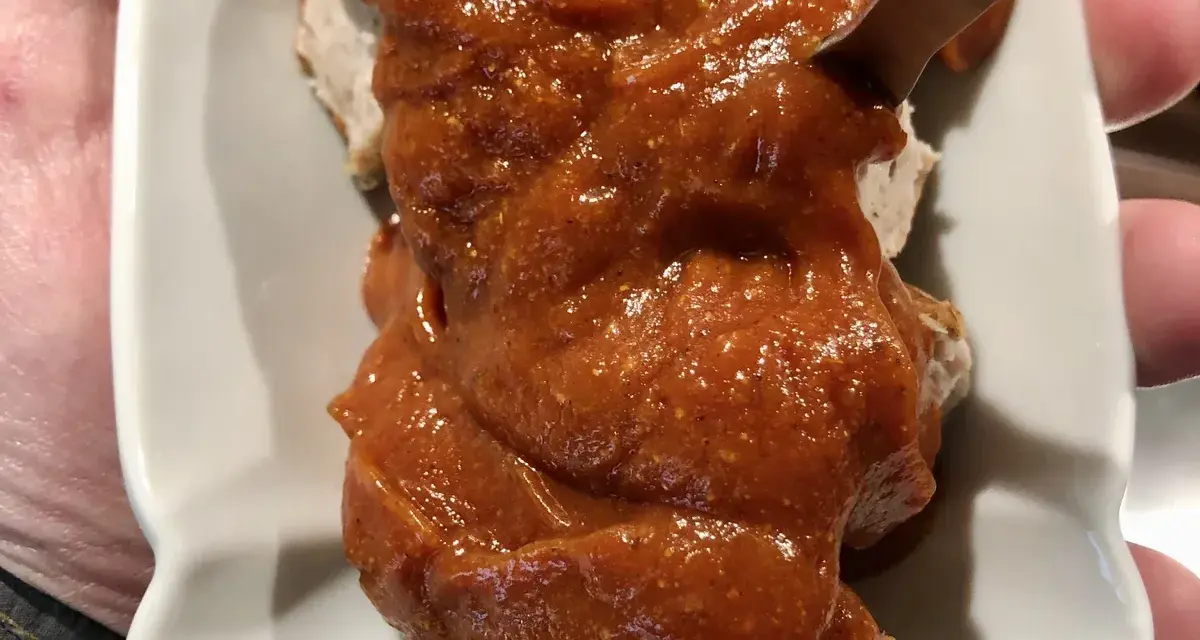 Eine Portion Currywurst mit viel Sauce, die Lust auf das Currywurst Rezept macht.