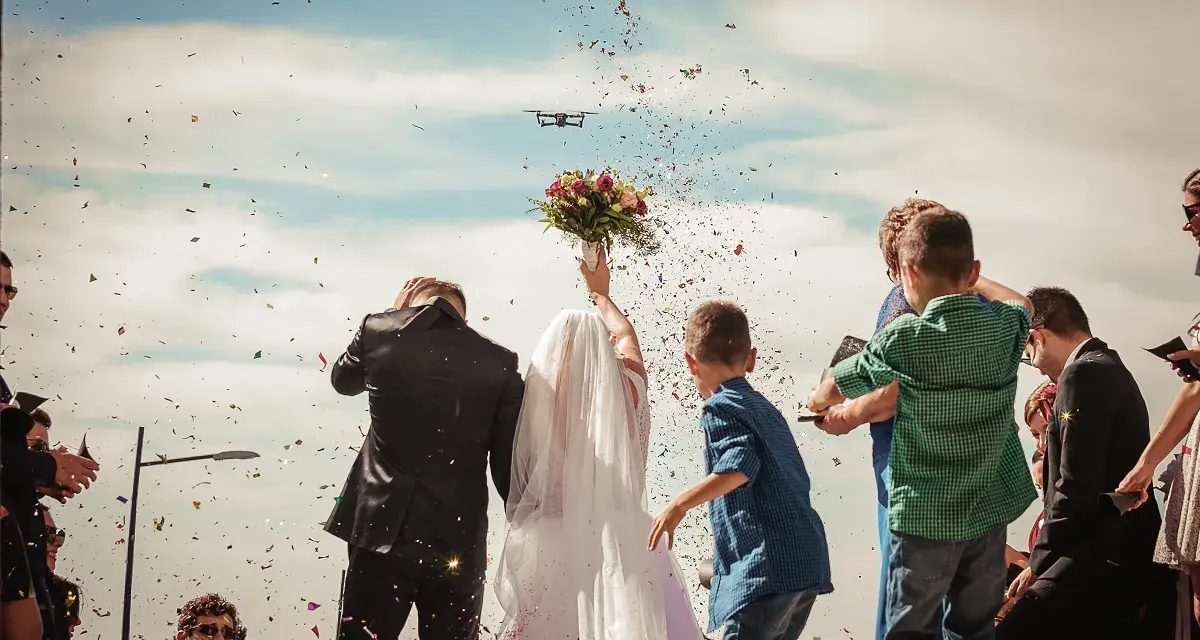 Para młoda w chmurze konfetti, dron filmuje ich wyjście. Stylowe zakończenie imprezy, jak zakończyć stylową imprezę efektownym wyjściem pary lub jubilata.