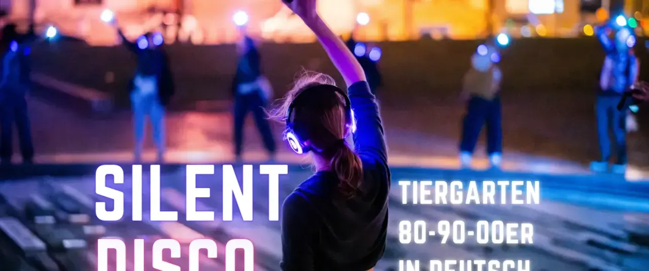 Silent Disco Berlin im Tiergarten. Leute tanzen mit leuchtenden Kopfhörern im Dunkeln.