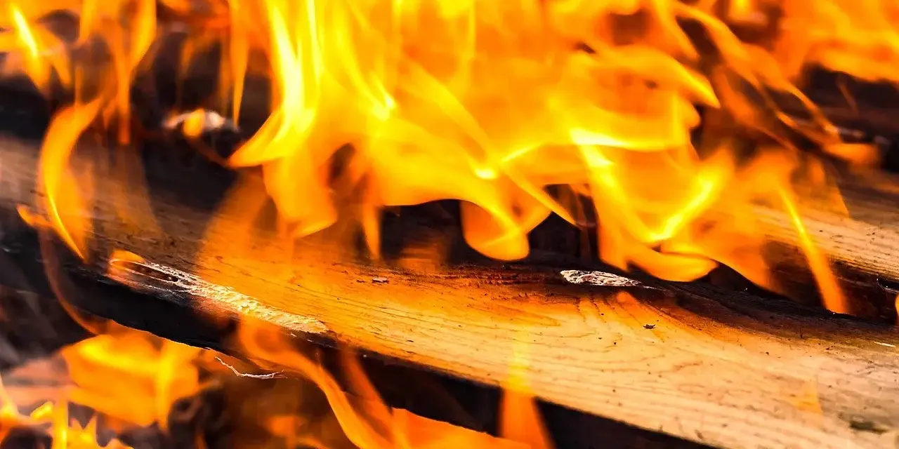 Płomienie tańczą na drewnie, uwalniając zapach kreozotu.