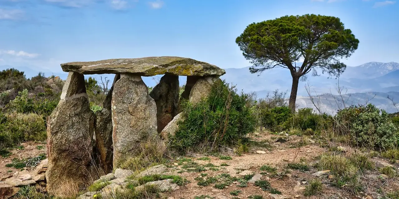 Starożytny menhir, kamienna konstrukcja, stoi na wzgórzu pod błękitnym niebem.