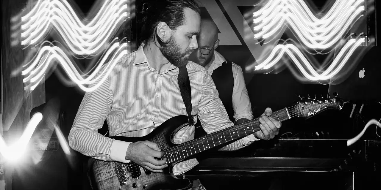 Muzyk gra na gitarze, a świetlne smugi tworzą efekt ruchu na zdjęciu.