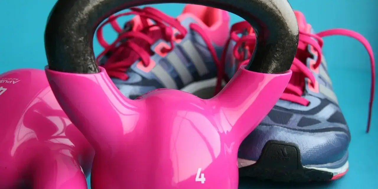 Różowe kettlebelle i buty sportowe marki Adidas gotowe do treningu.