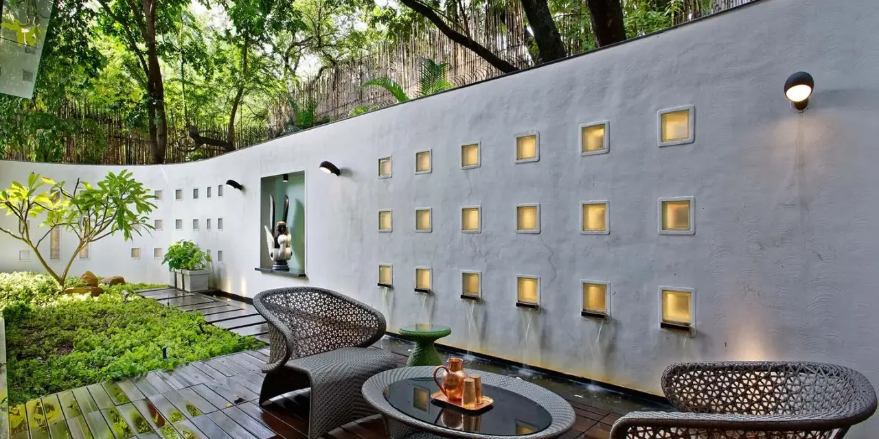 Un oasis moderno para decorar pared terraza pequeña. Muebles de mimbre, plantas exuberantes y cascadas de agua crean un ambiente sereno.
