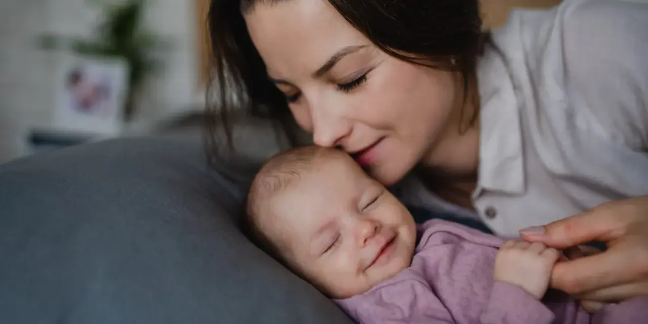 Mama całuje śpiące dziecko. Wkrótce wybierzemy dla niej słodkie imiona dla dziewczynki.