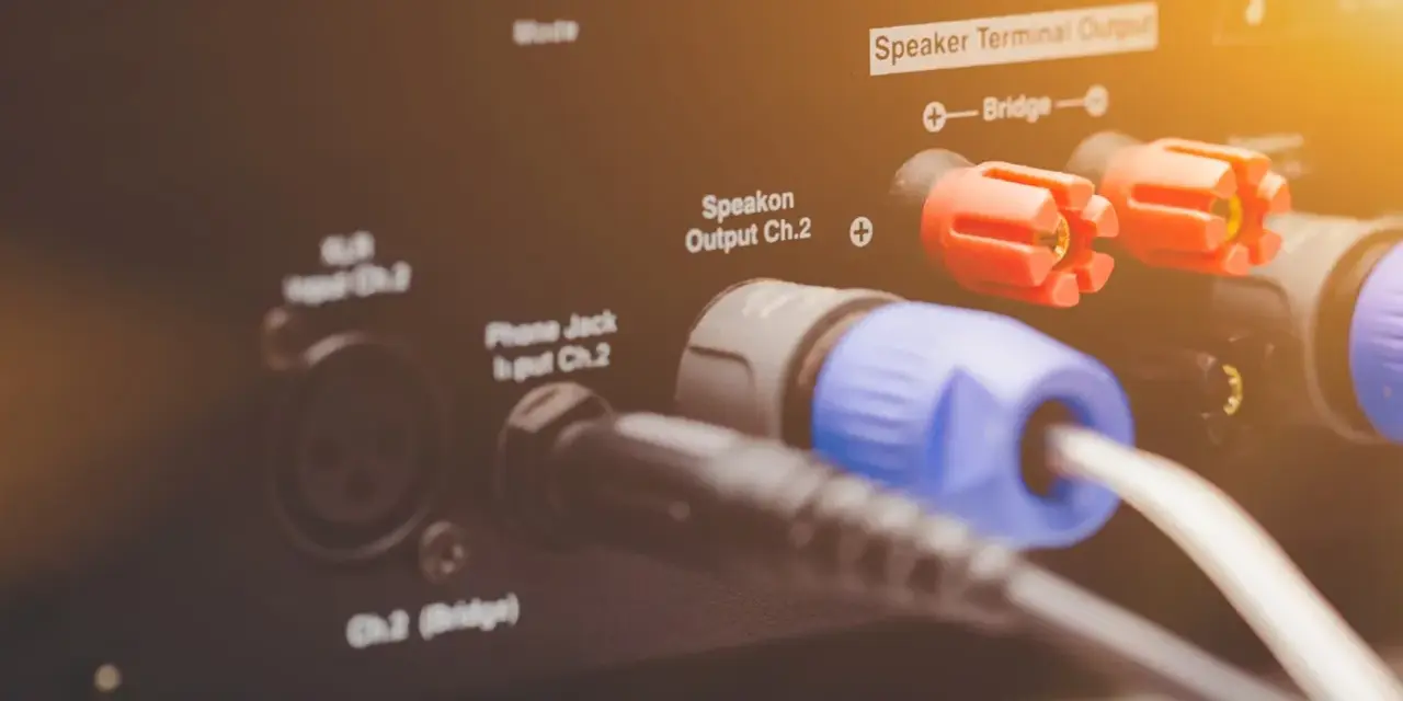 Złącza Speakon i zaciski głośnikowe na wzmacniaczu, pokazujące różne **cable types** do podłączenia sprzętu audio.