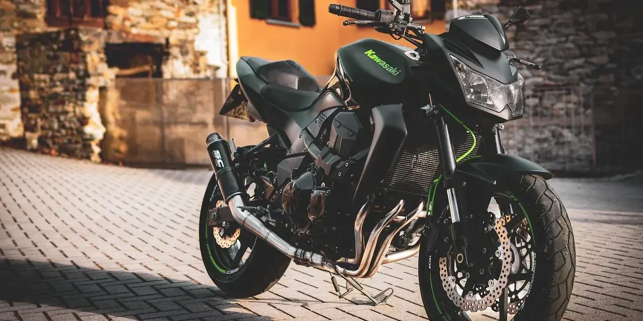 Czarny motocykl Kawasaki na brukowanej ulicy, z budynkami w tle.