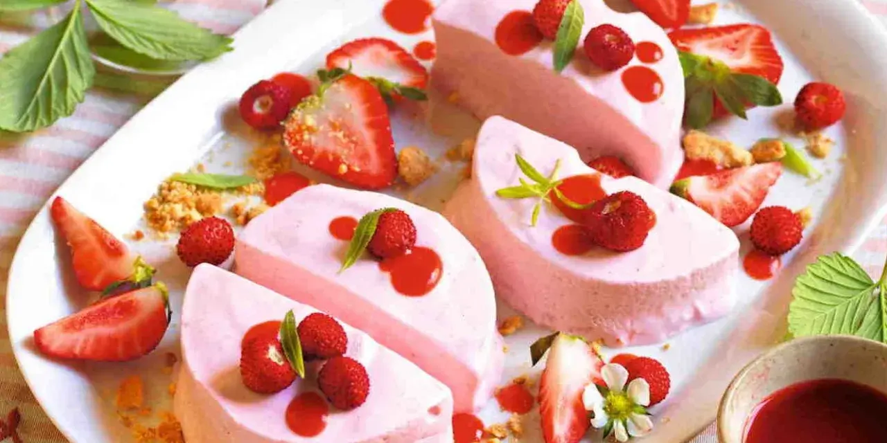 Delizioso semifreddo alle fragole, guarnito con fragoline di bosco, salsa rossa e foglioline verdi.