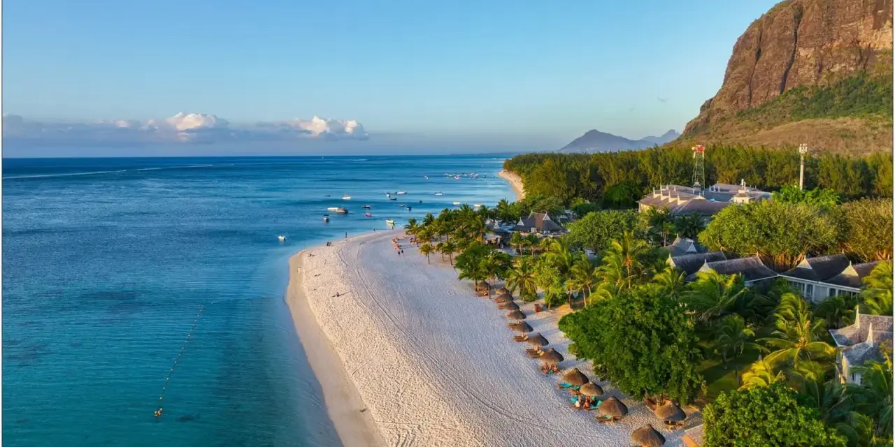 Rajska plaża na Mauritiusie, idealna temperatura do opalania. Woda kusi turkusowym blaskiem, a palmy szumią na wietrze.
