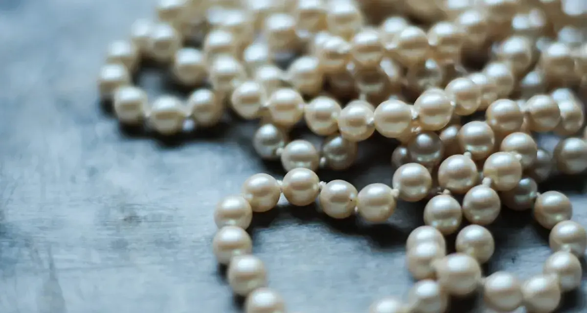 Collana di perle su sfondo grigio. Scopri come pulire la madreperla per mantenerla splendente.