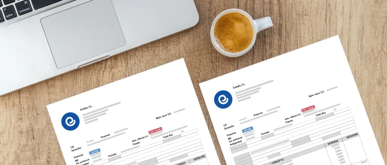 Documentos de nómina listos para ser procesados con un programa para hacer nominas. Café y portátil sugieren un entorno de trabajo.