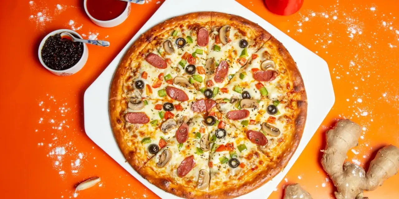 Gotowa pizza z kiełbasą, pieczarkami i papryką, obok sosy i imbir – idealne składniki na pizzę.
